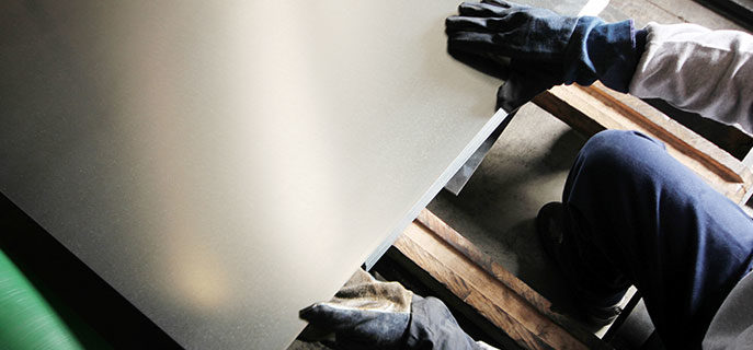 Man handling aluminum sheet using gloves